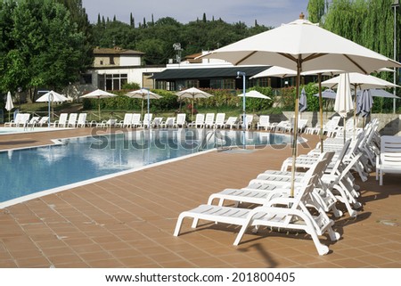 Pool and white sun loungers. Rounded shapes pool