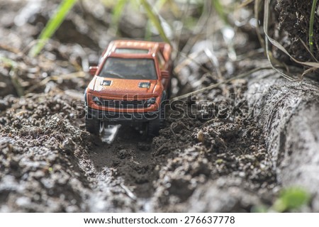Small red off road car toy in the nature. Miniature