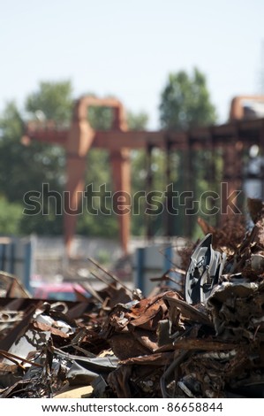 Pile of scrap iron and crane. Blurred background. Vertical image