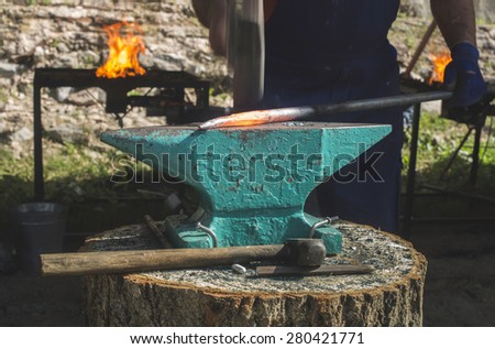 Blacksmith forges iron on anvil. Heated red iron