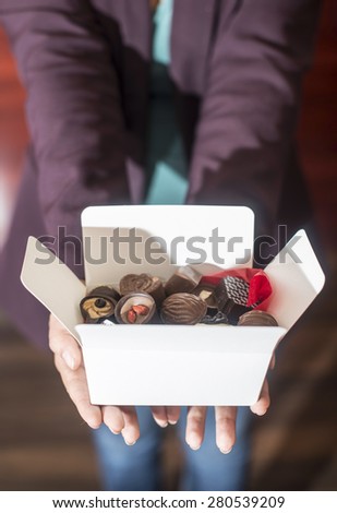 Hands holding a box of chocolates. Close up