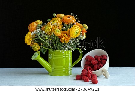 Fresh raspberries in a cup with  flowers in watering can