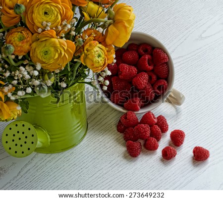 Fresh raspberries in a cup with  flowers in watering can