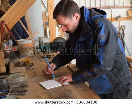 Portrait of a carpenter drawing on a sheet of paper in his workshop