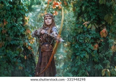 Woman hunter with a bow in hand, taking aim at his prey in the forest. Amazon with a bow in the hands of the forest.