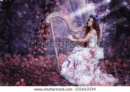beautiful brown-haired woman with a flower wreath on her head, wearing a white dress playing the harp in the forest