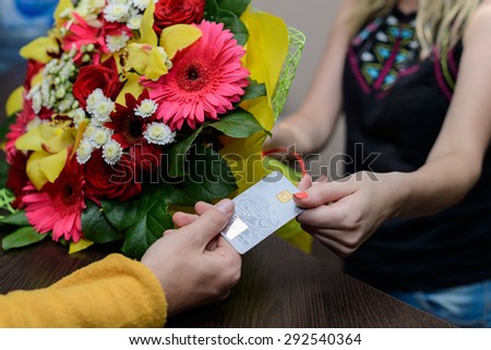 Young woman working as florist giving credit card to customer after purchase.