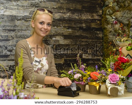 Florist accepts payment by credit card in a store flowers. Focus on the face of the model on the left