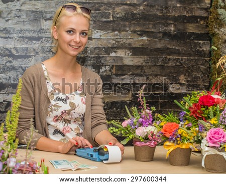 Florist girl breaks a check at the store flowers. Focus on the model of the left