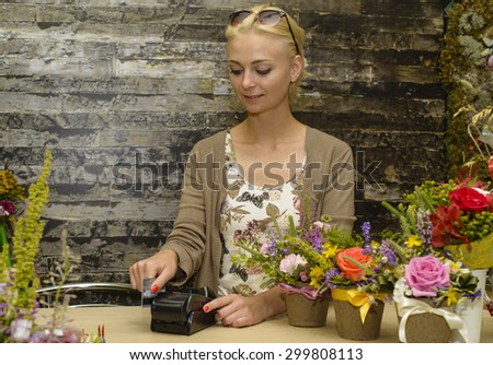 Florist accepts payment by credit card in a store flowers. Focus on the face of the model in the center