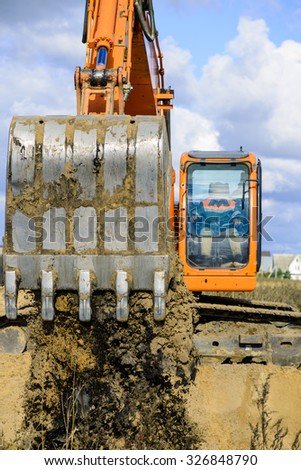 On the construction site - a bucket of an excavator digging a trench in closeup