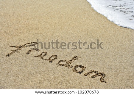Freedom message written in the sand blue ocean in the background