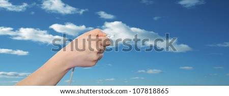 Concept or conceptual human or man hand holding a internet data cable in clouds over the blue sky, as a metaphor for plug,connection,technology,share,network,mobility,connectivity or communication