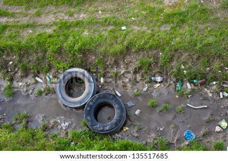 Concept or conceptual unhygienic polluted river,sewage or dirty water and grass with waste,trash and dump background,metaphor to pollution,environment,ecology,contamination,recycle,damage old problem