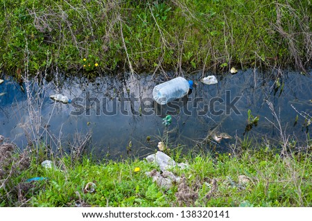 Concept or conceptual unhygienic polluted river,sewage or dirty water and grass with waste,trash and dump background,metaphor to pollution,environment,ecology,contamination,recycle,damage old problem
