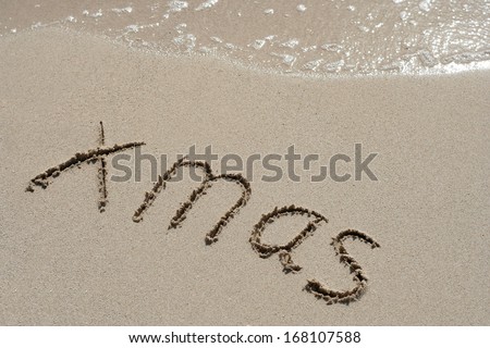 Concept or conceptual hand made or handwritten Xmas text in sand on a beach in an exotic island