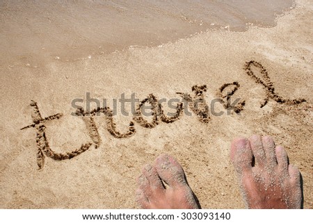 Travel hand written in sand on a beach on an exotic island background with feet