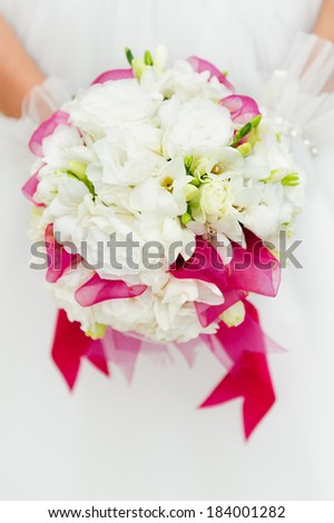 Wedding bouquet with white flowers in hands of bride