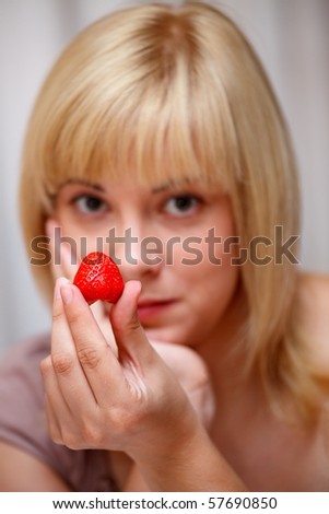 Beautiful blonde girl tempts us fresh  red strawberry