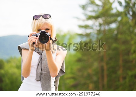 Cute girl taking a picture using SLR camera outdoors