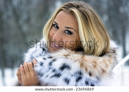 Blond girl wearing white fur coat in winter