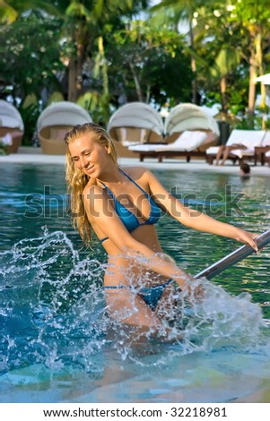 Beautiful blonde girl in the pool making splashes
