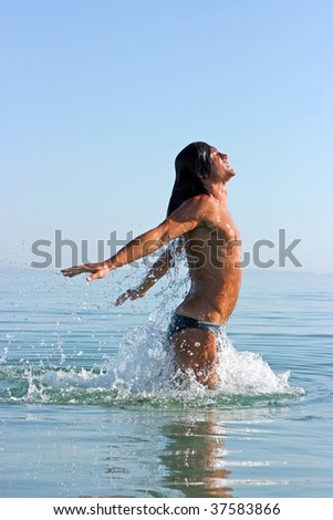Muscular handsome man jumping out of the sea