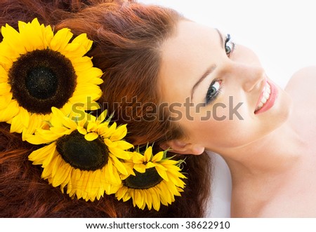 Close-up beautiful luxury fresh bright young lady in studio shot with sunflowers in her red long hair