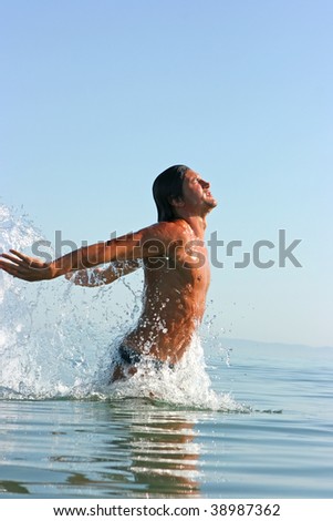 Muscular handsome man jumping out of the sea