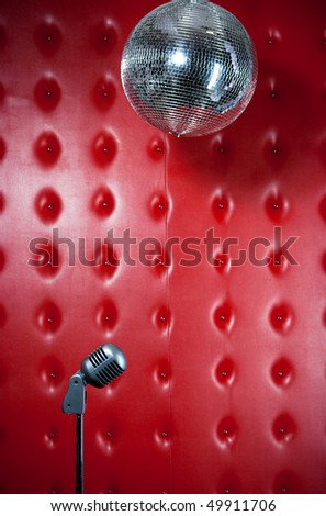 Interior of a club with red leather wall, microphone and disco ball