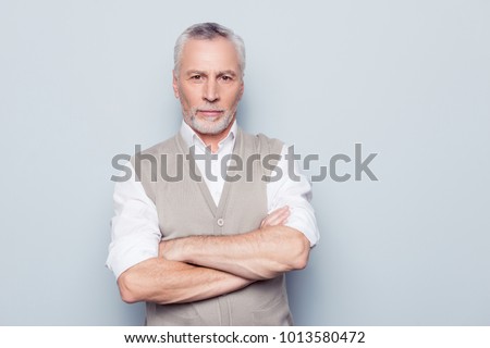 People individual lifestyle concept. Portrait of virile serious minded self-assured pensive granddad with crossed hands beige knitted waistcoat isolated on gray background copy-space