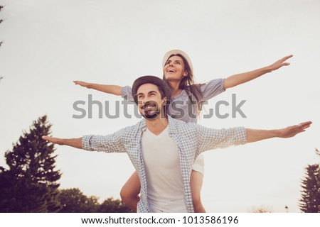 Good day, happiness, friendship, stroll, holiday concept. Cute sweet partner piggybacking his lady, she rides him, they are well dressed, excited, lovely, with spread hands