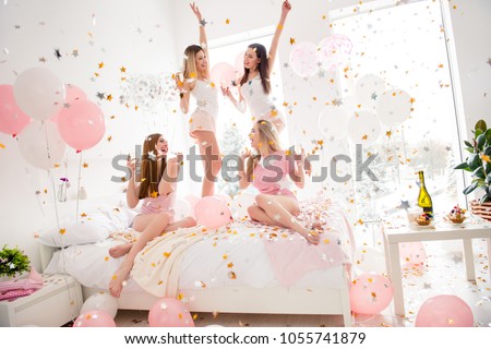 Cheerful, cool, sexy, pretty, charming, funky girls in night wear enjoying rain of colorful stars, confetti having theme party meeting indoor, drinking alcohol, dancing, laughing