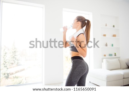 Jogger run runner energy sweaty yoga vitality wellness concept. Side profile view photo portrait of sexual attractive beautiful glad sportive woman holding bottle in hand standing in white room