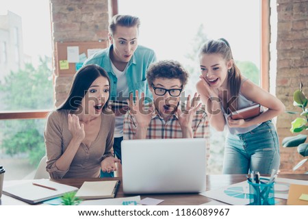 WOW! I cant believe it! Emotional, rejoice and glad group of collaboration students looking at the monitor with open mouth stand in casual trendy denim wear