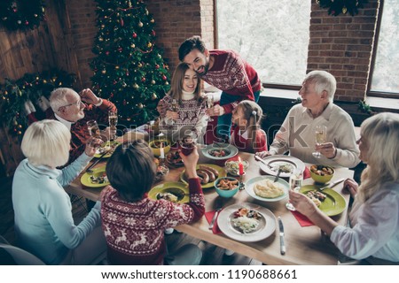 High above angle view merry noel family gathering friends couples. Cheerful grey-haired grandparents, grandchildren brother sister daughter son saying toast embracing wife fun joy house feast congrats