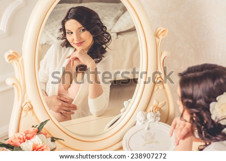 Pregnant looking in the mirror in the bedroom