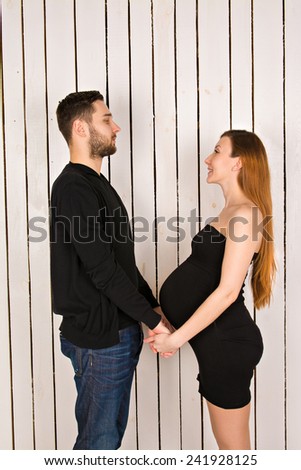 man holding hands his pregnant girl. Young future parents holding hands and looking at each other. couple in love in an elegant black clothes