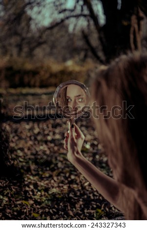 witch looks in the mirror in a dark forest