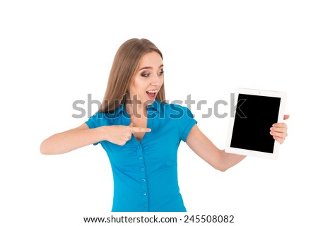 Presenting her brand new tablet. Young beautiful businesswoman surprised holding digital tablet and pointing it while standing isolated on white