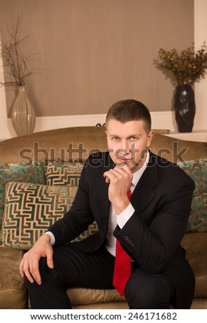 Thoughtful businessman. thoughtful young man in formal wear holding hand on chin and smiling