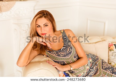 beautiful girl sitting on a white leather couch.