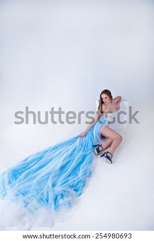 beautiful girl in a blue long dress with plume on a white background