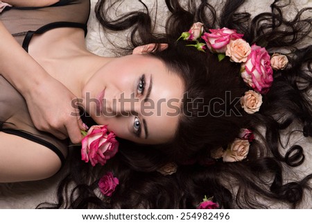 girl with a circlet of flowers on head. charming girl with a flowers. young woman has a beautiful face. girl lying on fur with her long hair