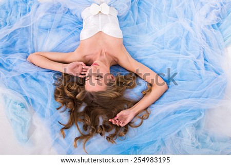 beautiful girl lies on plume of her long dress
