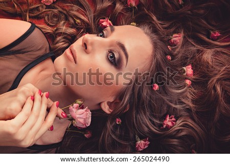 hair with roses expand on the fabric colored Marsala. top view image of a girl with long curly hair.