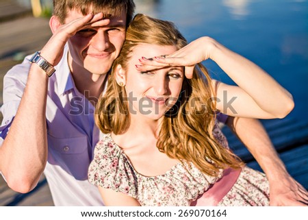 Man and woman squinting from the sun. couple in love closed eyes with hand from the sun