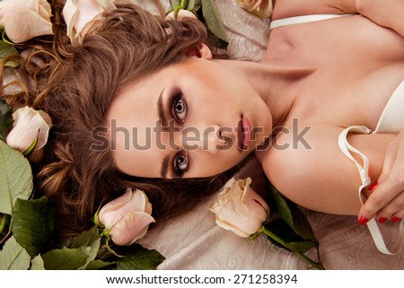 girl with roses.  image top view of a girl who is lying in lingerie on the bed with roses