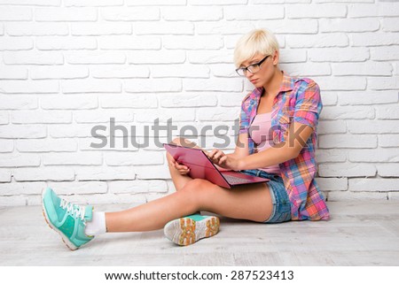 Top view of young woman siting on the floor and working at a lapt