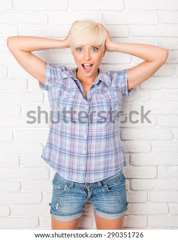 Surprised young woman holding hands in hair